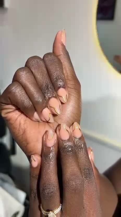 Elegant almond nails in peach nude with gold wavy line art