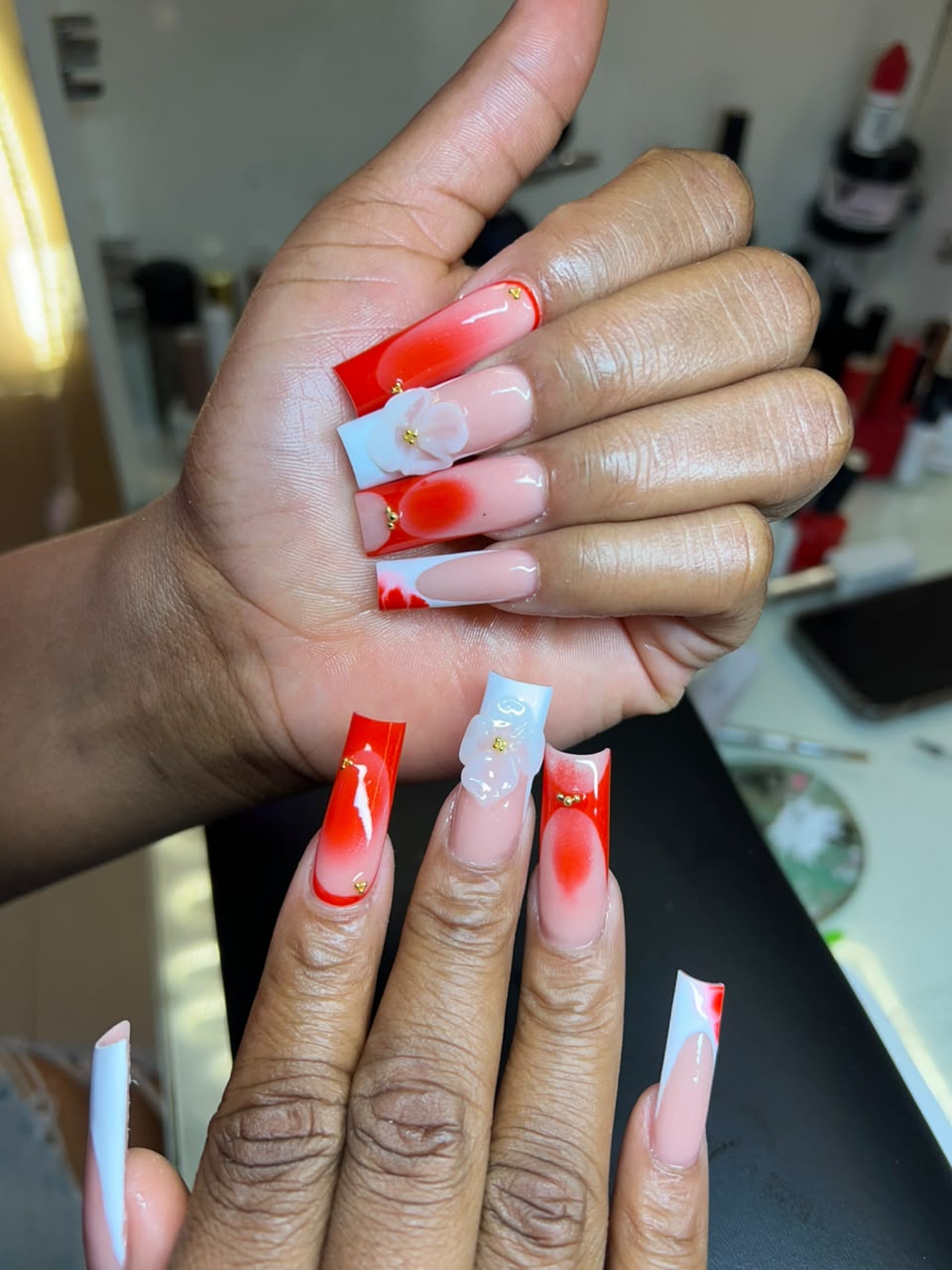 Long square acrylic nails in red and white with 3D camellia flowers and gold accents