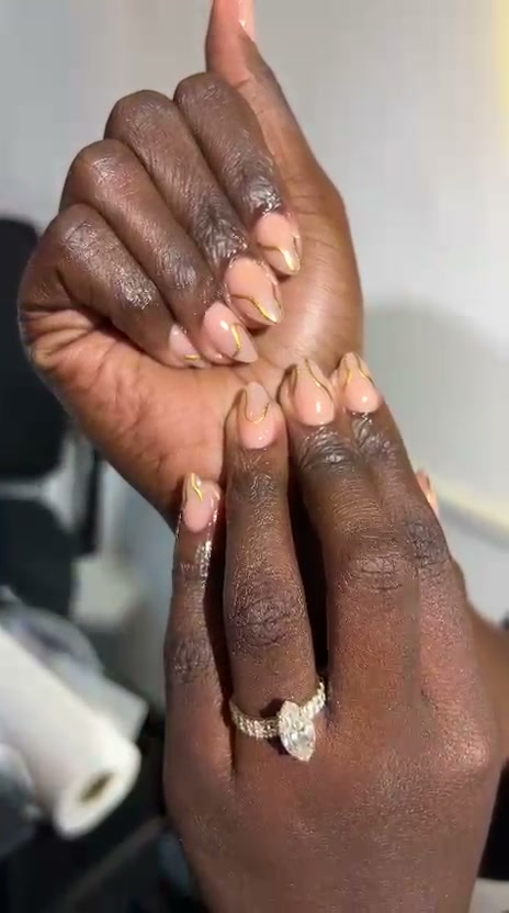 Nude almond nails with gold swirl design